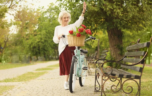 Hermosa mujer de mediana edad agitando su mano en el parque — Foto de Stock