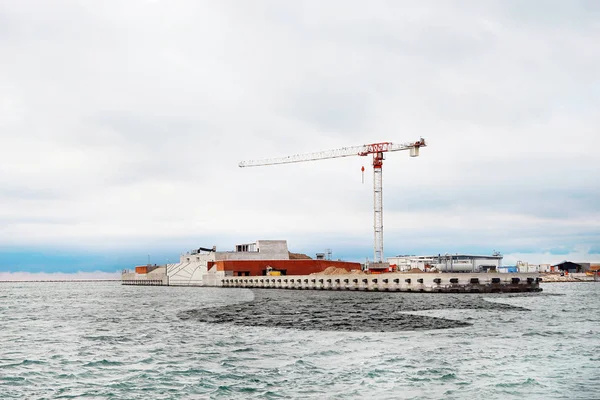 Construction site by sea and oil spill on water — Stock Photo, Image