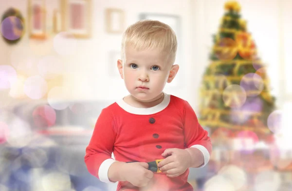 Schattige baby in kostuum van Santa's helper en kerstboom op achtergrond. Vakantie feest concept — Stockfoto