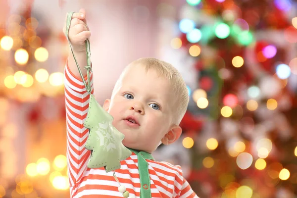 Bambino carino con giocattolo e albero di Natale sullo sfondo. Concetto festivo — Foto Stock