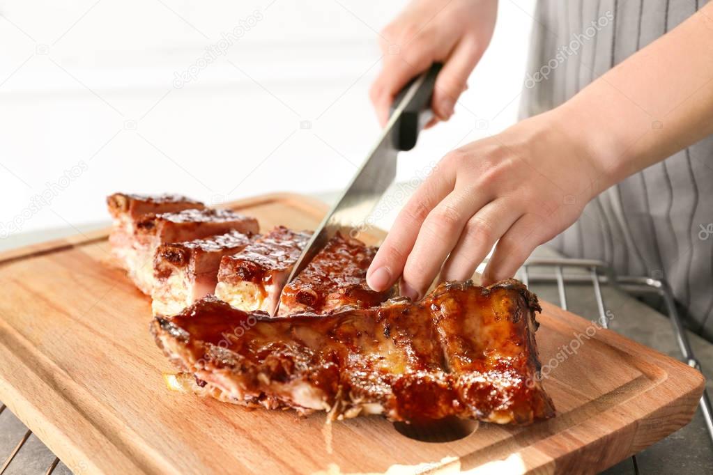 Woman cutting delicious pork ribs