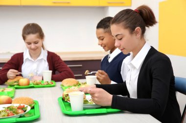 Öğle Yemeği yerken okul kafeteryasında masada oturan çocuk