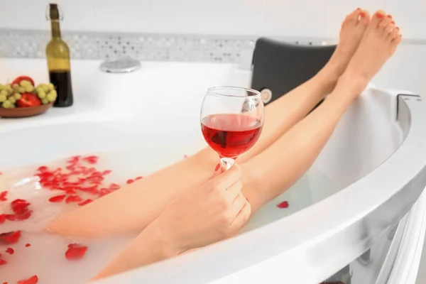 Jovem deitada na banheira e bebendo vinho — Fotografia de Stock