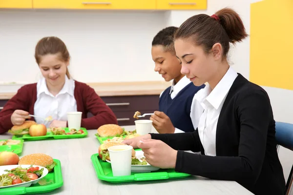 Öğle Yemeği yerken okul kafeteryasında masada oturan çocuk