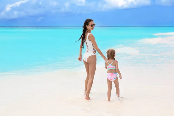 Hermosa joven con su hija en la playa en el balneario — Foto de Stock