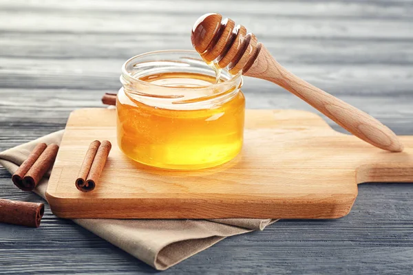 Vaso con miele dorato e cannella sul tavolo di legno — Foto Stock