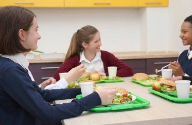 Öğle Yemeği yerken okul kafeteryasında masada oturan çocuk