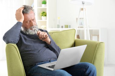 Dizüstü bilgisayar ile koltuk otururken yakışıklı yaşlı adam
