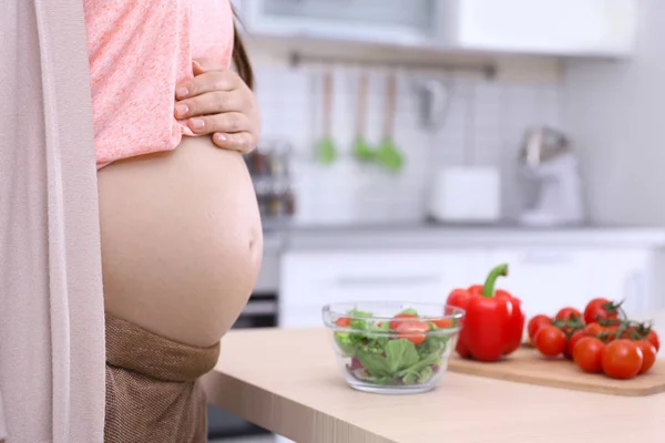 Беременная девушка, стоящая рядом с столом с завтраком — стоковое фото