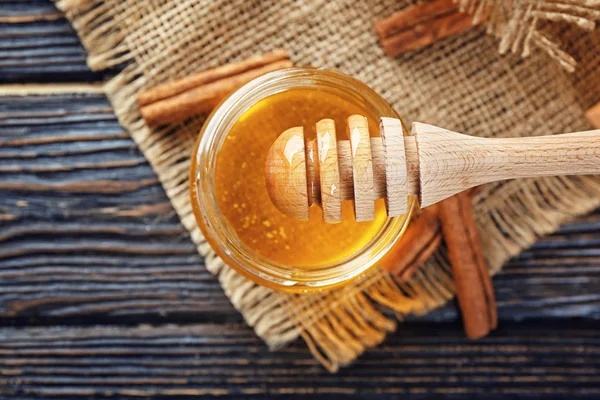 Mel dourado e canela na mesa de madeira — Fotografia de Stock