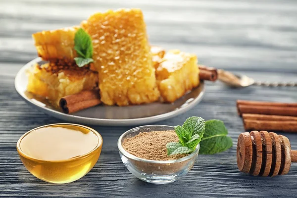 Bowls with golden honey and cinnamon powder on wooden table — Stock Photo, Image