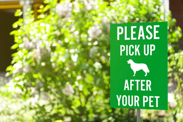 Signboard with text PLEASE PICK UP AFTER YOUR PET — Stock Photo, Image
