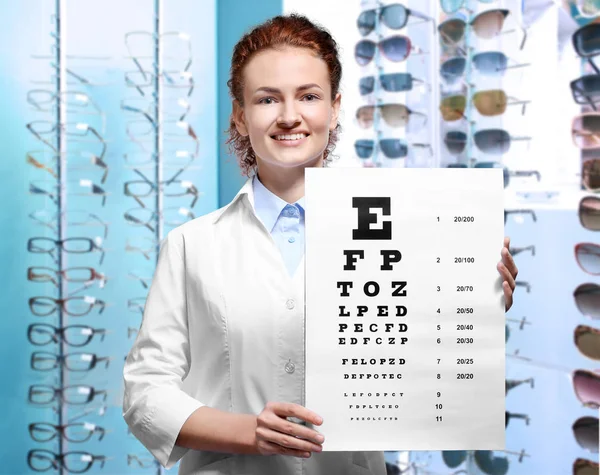 Офтальмолог с диаграммой зрения в оптическом магазине — стоковое фото