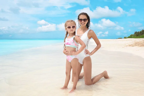 Hermosa joven con su hija en la playa en el balneario — Foto de Stock