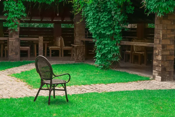 Sedia confortevole su erba verde vicino al patio caffè nel parco — Foto Stock