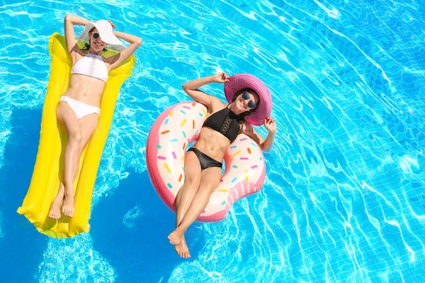 Belles jeunes filles avec beignet gonflable et matelas dans la piscine bleue — Photo
