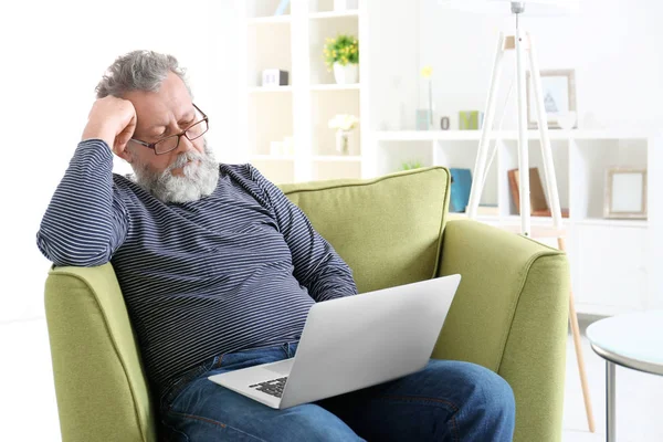 Dizüstü bilgisayar ile koltuk otururken yakışıklı yaşlı adam — Stok fotoğraf