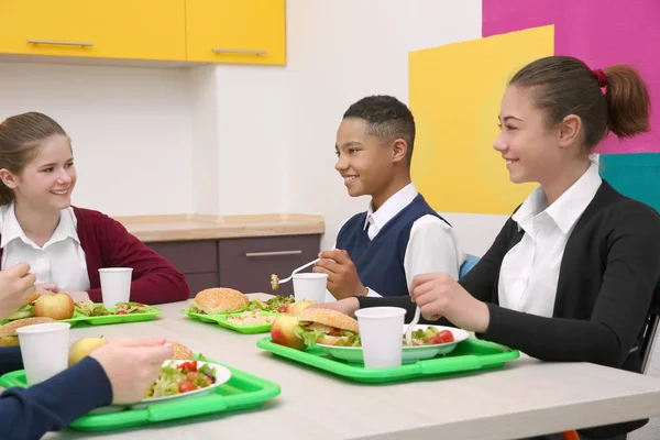 Öğle Yemeği yerken okul kafeteryasında masada oturan çocuk