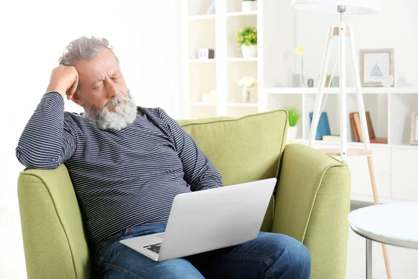 Pria tua yang tampan duduk di kursi berlengan dengan laptop — Stok Foto