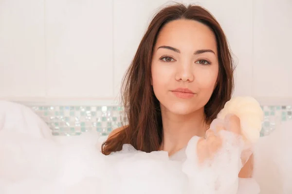 Schöne Frau entspannt sich in der Badewanne mit Schaum — Stockfoto