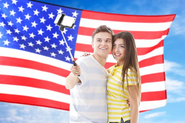 Pareja joven virando selfie y bandera de EE.UU. en el fondo —  Fotos de Stock