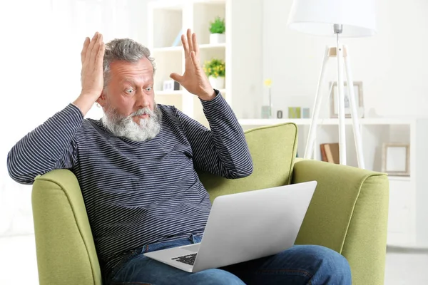 Vacker äldre man sitter i fåtölj med laptop — Stockfoto
