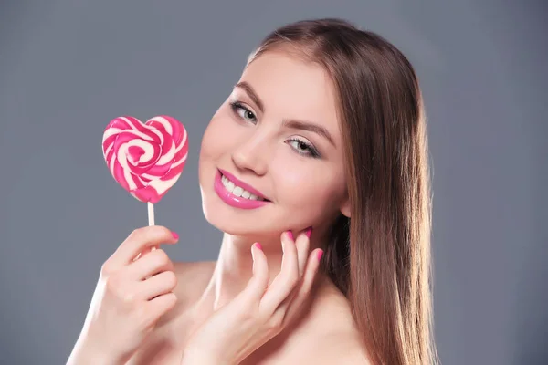 Bella giovane donna con lecca-lecca su sfondo a colori — Foto Stock