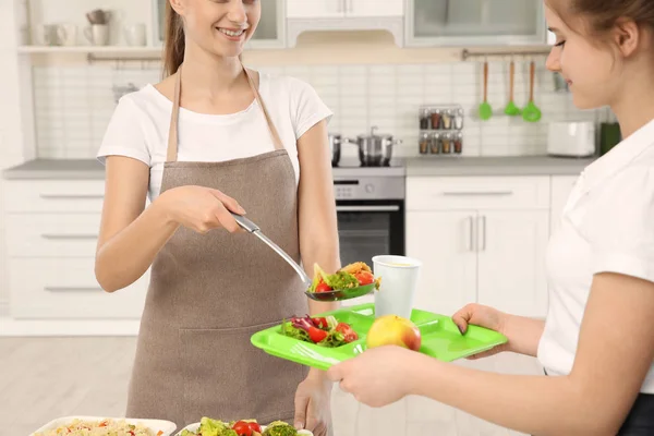 Giovane donna che serve il pranzo alla ragazza della scuola in mensa — Foto Stock