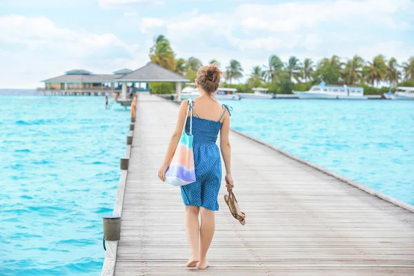 Vacker ung kvinna promenader längs ponton till sjöss resort — Stockfoto