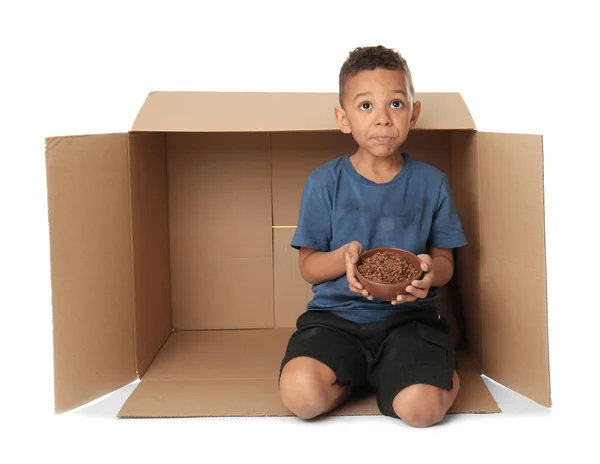 Милый маленький мальчик, живущий в коробке на белом фоне. Концепция бедности — стоковое фото