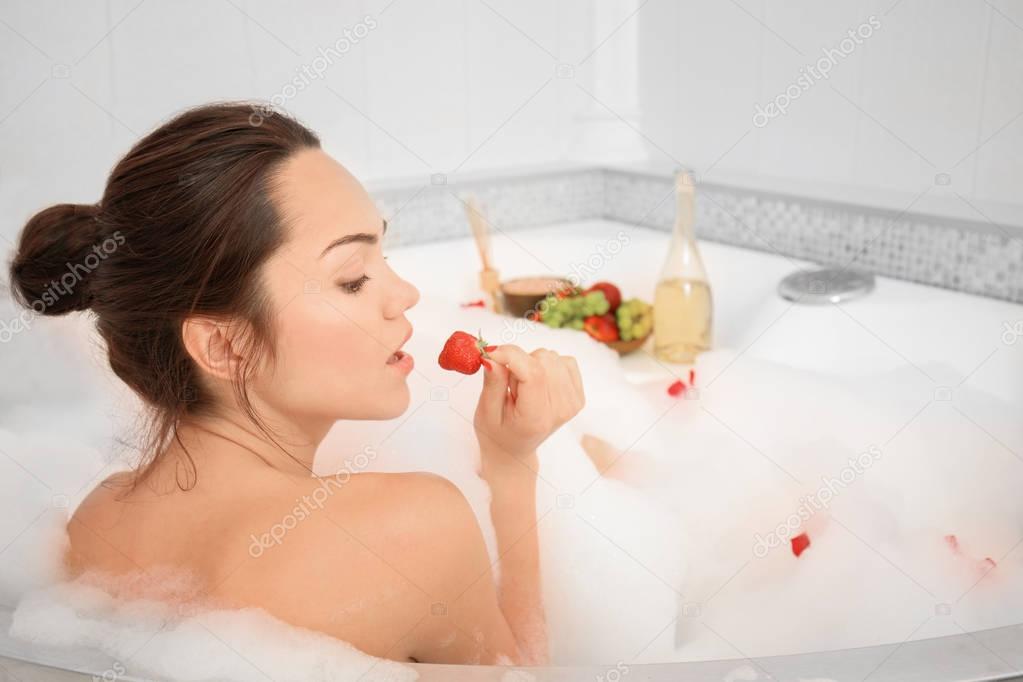 Beautiful woman with strawberry in bathtub