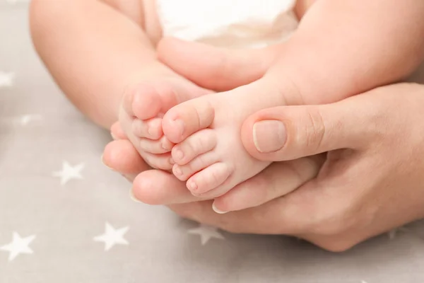 Madre manos sosteniendo poco bebé piernas — Foto de Stock