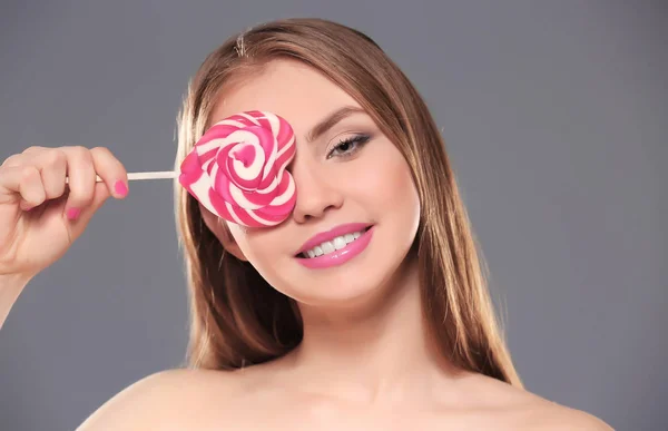 Hermosa mujer joven con piruleta sobre fondo de color —  Fotos de Stock