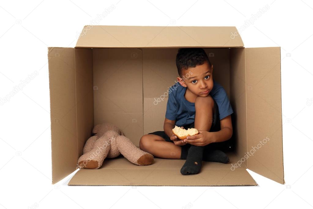 Cute little boy living in box on white background. Poverty concept