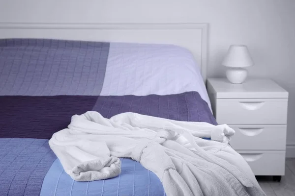 Белый халат на кровати — стоковое фото