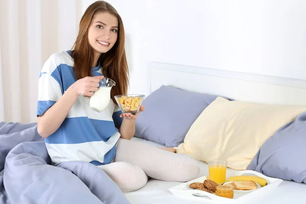Молодая красивая женщина завтракает в постели — стоковое фото
