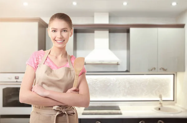 Jonge vrouw in schort met spatel op keuken thuis — Stockfoto