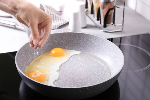 Ручная добавка соли к яйцам — стоковое фото