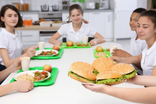 在学校食堂为儿童提供美味三明治的妇女 — 图库照片