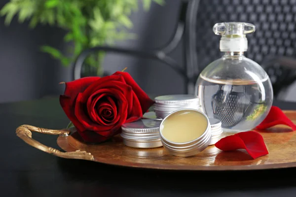 Tray with perfume bottle, containers and rose on dark table — Stock Photo, Image
