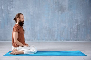 Genç adam gri duvar arka plan üzerinde Yoga uygulamak