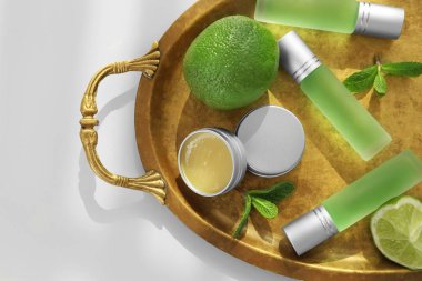 Tray with perfumes, limes and mint leaves on light background clipart