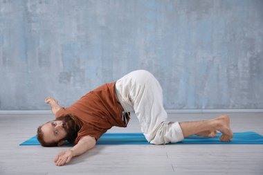 Genç adam gri duvar arka plan üzerinde Yoga uygulamak