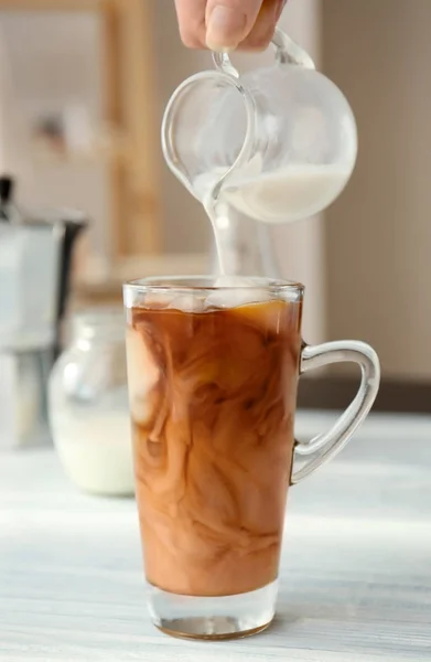 Despejar leite em copo de vidro com café — Fotografia de Stock