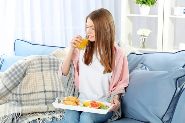 Joven hermosa mujer desayunando en el sofá — Foto de Stock