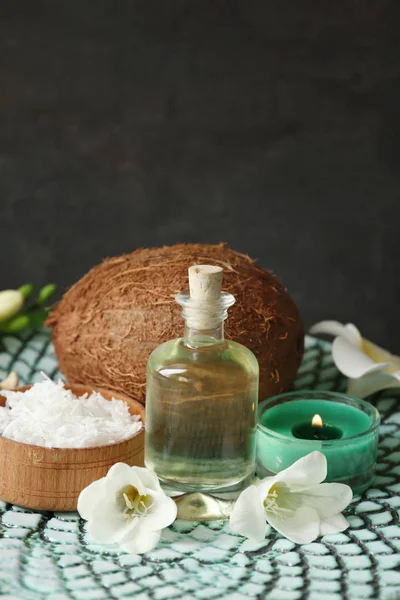 Бутылка с маслом, высушенный кокос и свечи на сером фоне — стоковое фото
