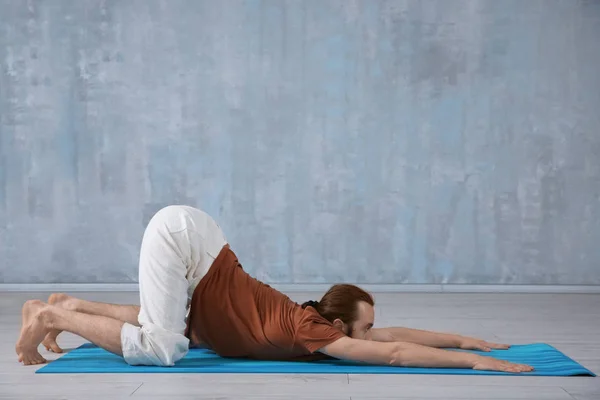 Jonge man het beoefenen van yoga op grijze muur achtergrond — Stockfoto