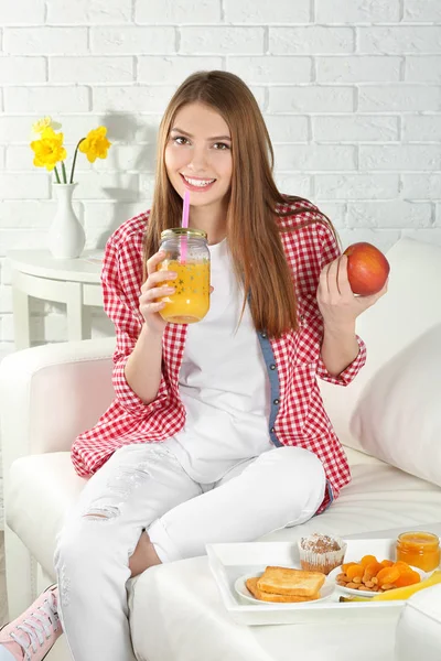 Joven hermosa mujer desayunando en el sofá — Foto de Stock