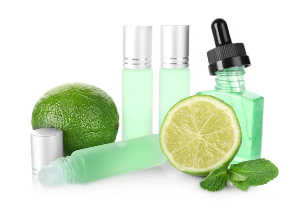 Botellas con perfume, hojas de menta y lima sobre fondo blanco — Foto de Stock