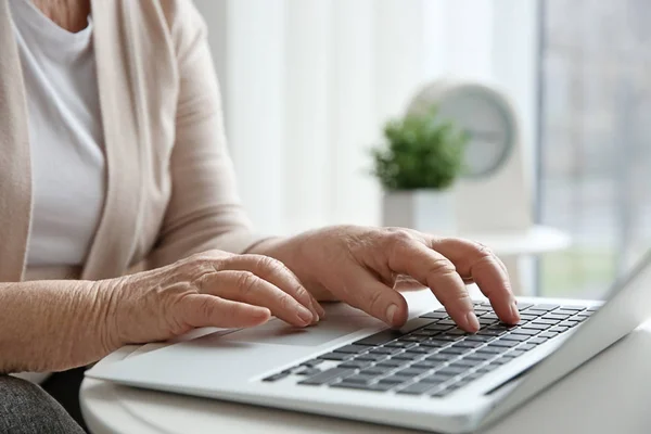 Mulher sênior usando laptop na mesa — Fotografia de Stock